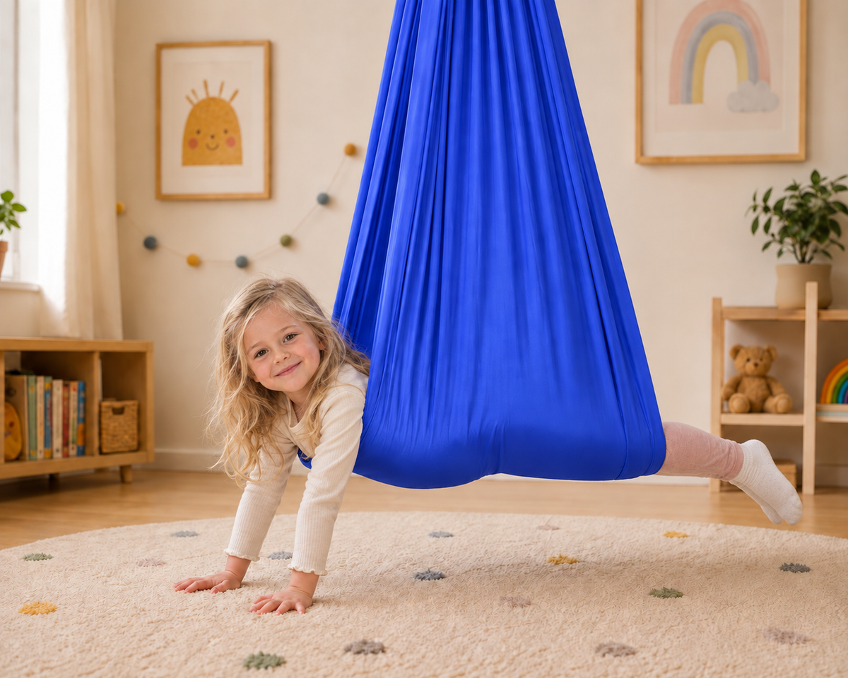 Mädchen liegt bäuchlings im royalblauen Tuch und stützt die Hände auf dem Teppich ab