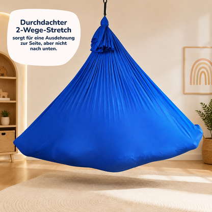 Kind liegt im komplett ausgedehnten royalblauen Tuch im Kinderzimmer, daneben der Hinweis: Der 2-Wege-Stretch dehnt sich zur Seite, aber nicht nach unten