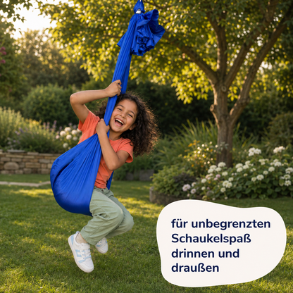Mädchen schwingt lachend im royalblauen Tuch, im Garten an einem Baum aufgehängt